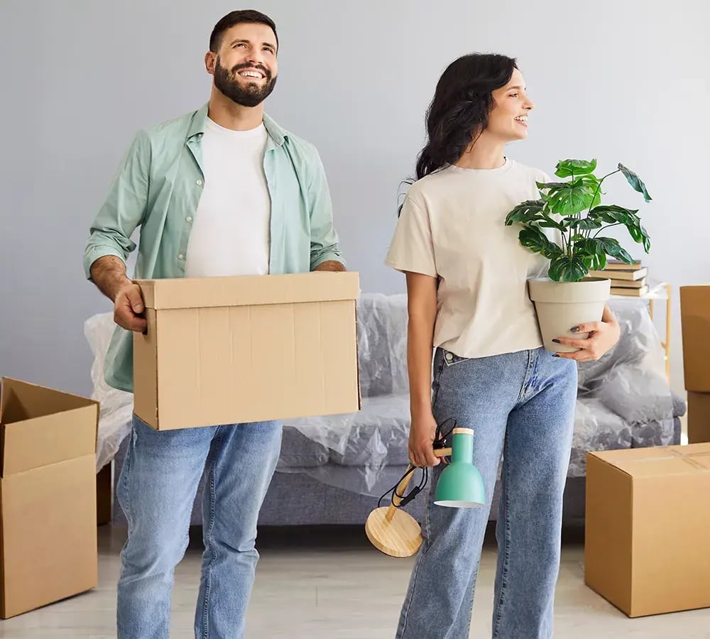 A couple with moving boxes, looking happy to be in a new home