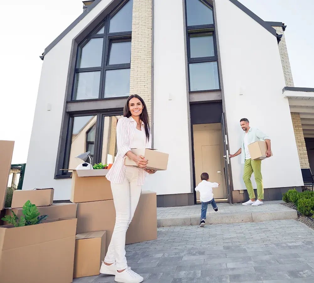 Family Moving Boxes Into Home